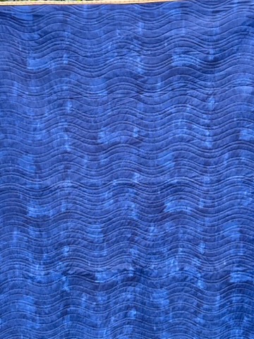 Reverse of Bright Flowers quilt showing deep blue fabric with flowing wave-like quilting
