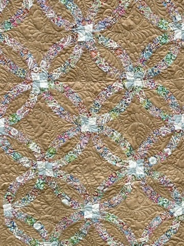 Close-up of the Double Wedding Ring Quilt showing floral ring intersections and dense decorative quilting