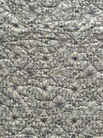 Close-up of the Halloween Wall Hanging showing dense free-motion quilting over ornate spiderweb and scrollwork fabric