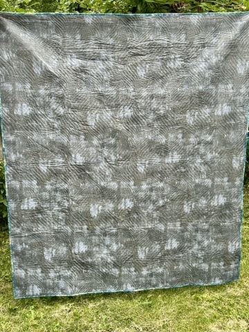 Reverse of Triangle Frenzy quilt showing a gray and white abstract patterned backing