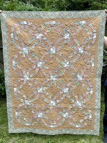 Double Wedding Ring Quilt by Michele Urbany Neely Puluti, featuring interlocking floral rings on a warm tan quilted field