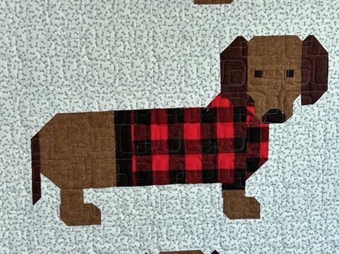 Close-up of a dachshund in red-and-black buffalo plaid on the Weiner Dogs Baby Quilt