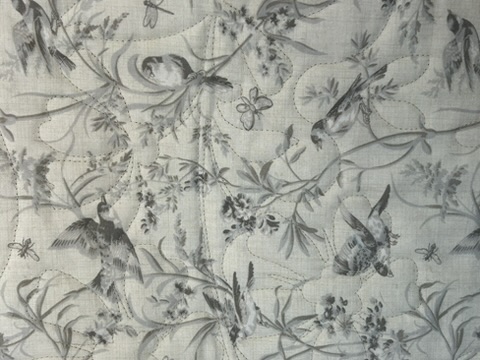 Reverse of The French General Quilt showing pale bird-and-botanical fabric with stitched quilting
