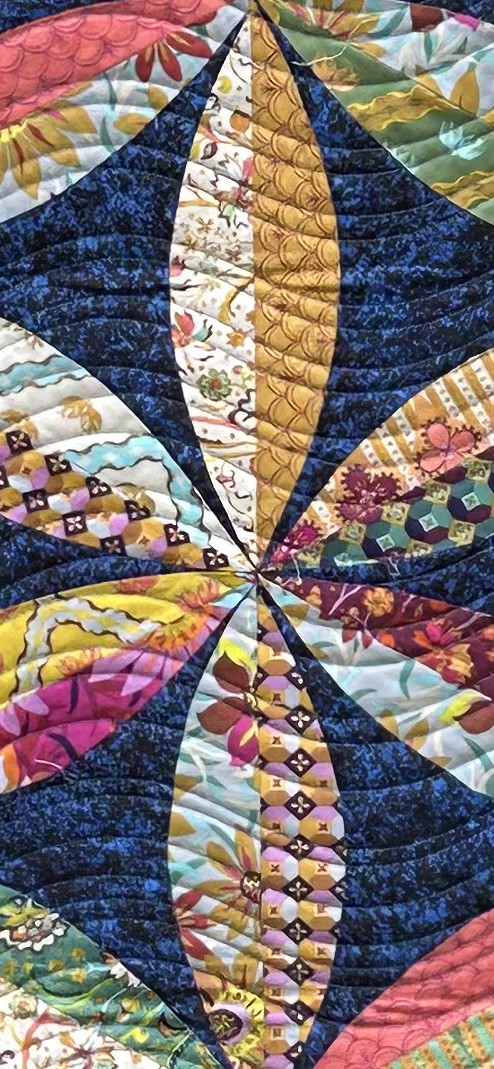 Close-up of Bright Flowers quilt showing multicolored curved piecing and dense decorative quilting